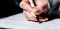 Main blanche avec vernis beige écrit dans un cahier de notes avec un crayon noir et blanc