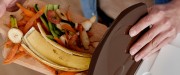 Personnes blanches placent des résidus de fruits et légumes dans un petit bac de compost beige