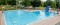 À l'extérieur, vue en hauteur d'une piscine au fond turquoise avec trois chaises de sauveteurs et une grande glissade bleue et jaune