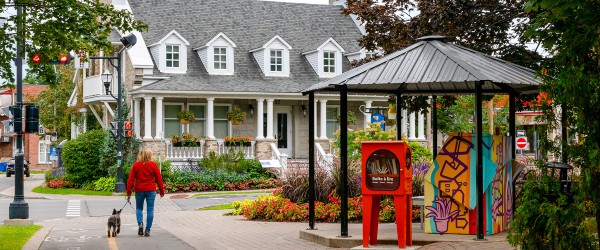 Place Lagoa avec vue sur la Maison Lachaîne, un piano public coloré, une boîte à lire rouge et une dame avec un manteau rouge qui promène son chien