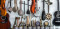 Sur un mur blanc, plusieurs instruments de musique sont accrochés dont des guitares, violons et tamtams.