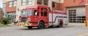 Devant la caserne de pompiers, un camion de pompiers rouge est stationné