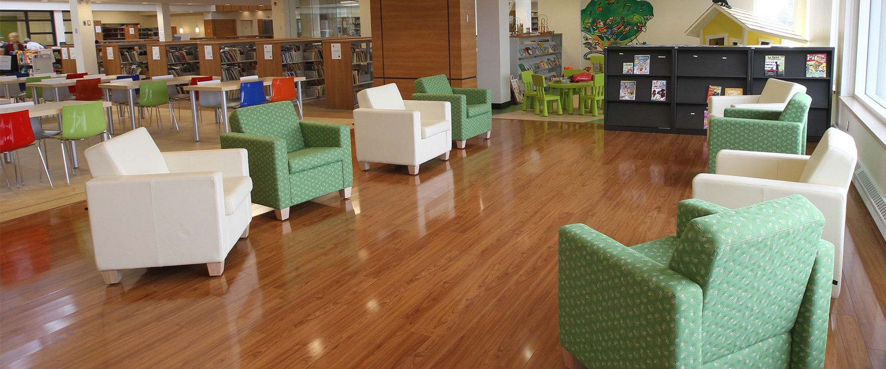 Dans la bibliothèque, des fauteuils verts et blancs sont placés en cercle