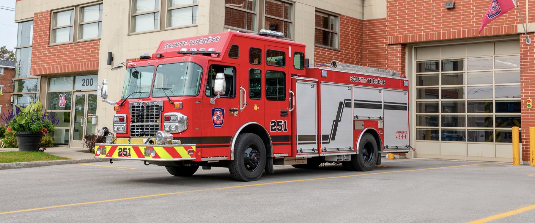Devant la caserne de pompiers, un camion de pompiers rouge est stationné