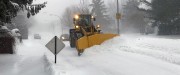 Sous un ciel gris, une souffleuse à neige jaune qui pousse la neige pour libérer la rue bordée de neige