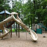 À l'extérieur, deux modules de jeux beige et vert avec glissades, stations d'escalade et d'équilibre