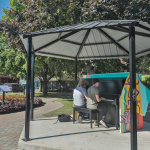 À L'extérieur sur une place publique, deux jeunes garçons jouent sur un piano peint de couleurs vives