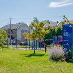 À l'extérieur, module de jeux bleu et rouge avec glissade, balançoires, stations d'escalade et d'équilibre