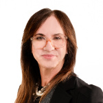 Femme blanche avec des cheveux châtains porte des lunettes transparentes et un blouson beige