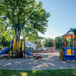 À l'extérieur, vue en hauteur d'une piscine au fond turquoise avec trois chaises de sauveteurs et une grande glissade bleue et jaune