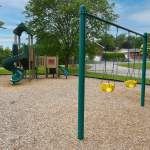 À l'extérieur, modules de jeux vert forêt avec glissades, quatre balançoires dont deux pour jeunes enfants