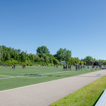 À l'extérieur, terrain de football fait de gazon synthétique avec estrades à droite