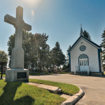 Un grand crucifix en pierre et une petite chapelle blanches surplombent les terrains gazonnés du cimetière