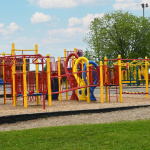 À l'extérieur, modules de jeux jaunes, bleus et rouges avec glissades, toile d'araignées et stations d'escalade