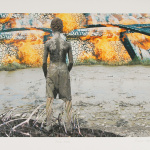 Jeune homme de dos recouvert d'argile regarde vers une structure de pierre en feu