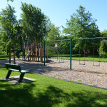 À l'extérieur, module de jeux beige, vert et jaune avec glissades et stations d'escalade