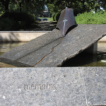 Sculpture en pierre à l'extérieur sur laquelle est inscrite le mot mémoire. Une pierre en angle se trouve au centre et est entourée d'eau.