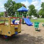 À l'extérieur, modules de jeux jaunes, rouges, verts et bleus avec des glissades, des stations d'escalade et un camion
