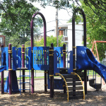 À l'extérieur, modules de jeux bleus, mauves, jaunes et rouges avec glissades, balançoires et stations d'escalade