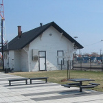 Petite cabane blanche au toit noir placé à côté d'un chemin de fer