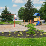 À l'extérieur, modules de jeux rouges, jaunes et bleus avec glissades, stations d'escalade et balançoires