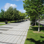 À l'extérieur, traverse piétonne en pavé uni teint pour donner l'apparence de touches de piano avec des arbres de chaque côté